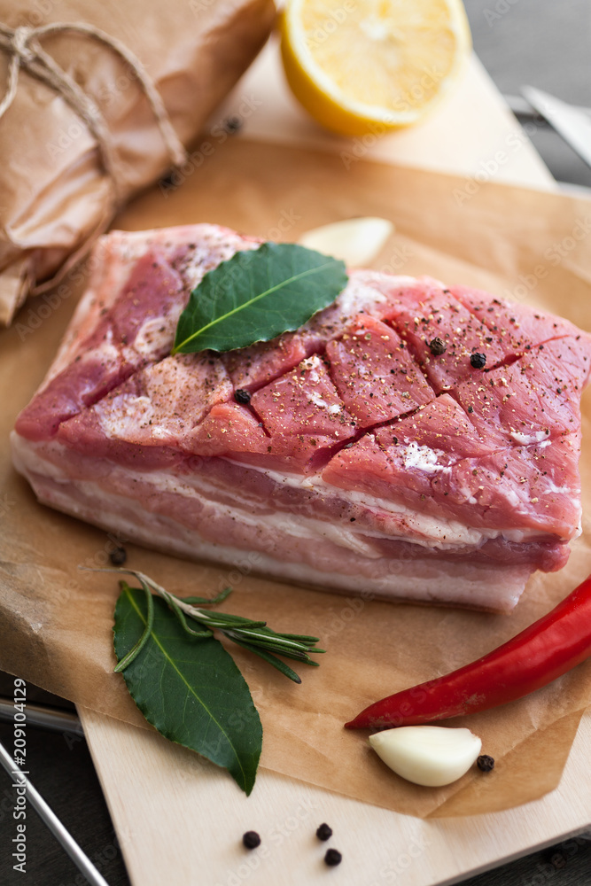 Raw pork bacon with spices and herbs on wooden background Raw pork bacon with spices and herbs on wooden background