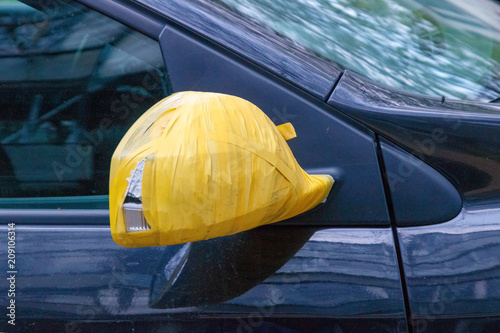 Repair the rear view mirror of the car with tape Black car, yellow duct tape..