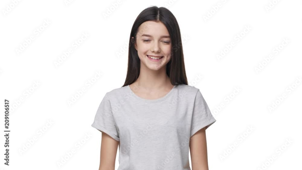 Portrait of beautiful teen girl in basic t-shirt smiling at camera and touching her long dark hair, isolated over white background in studio. Concept of emotions Portrait of beautiful teen girl in basic t-shirt smiling at camera and touching her long dark hair, isolated over white background in studio. Concept of emotions