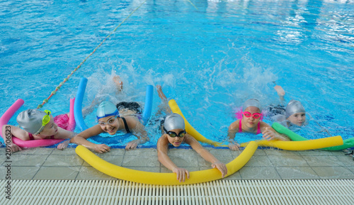 Happy children kids group at swimming pool class learning to swim