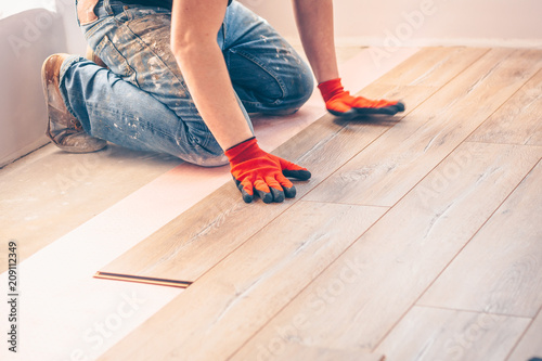 Working with hands installs a laminate board, professional flooring installation