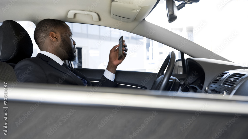 Driver waiting for boss, bored scrolling news application on his smartphone Driver waiting for boss, bored scrolling news application on his smartphone