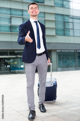 Successful adult businessman in suit with suitcase is is meeting his partner