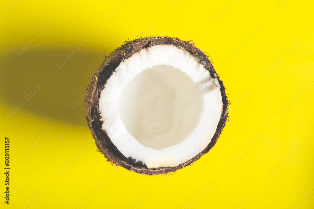 Half of coconut on a yellow minimalistic background Half of coconut on a yellow minimalistic background