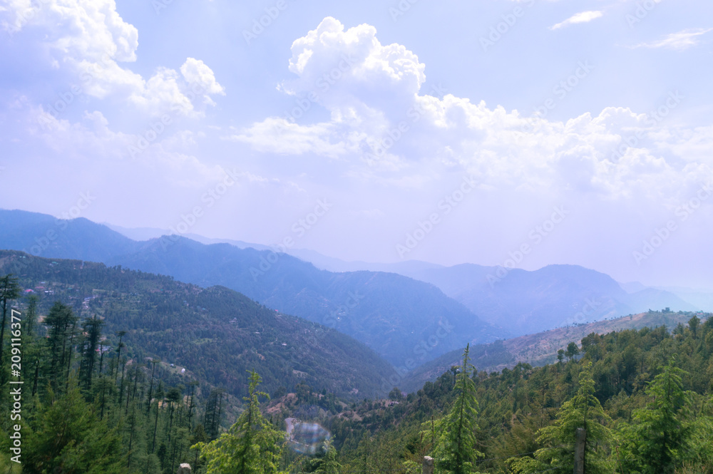 Landscape in shimla with mountains and trees shot against a cloudy sky. Perfect place for a hill station summer vacation
