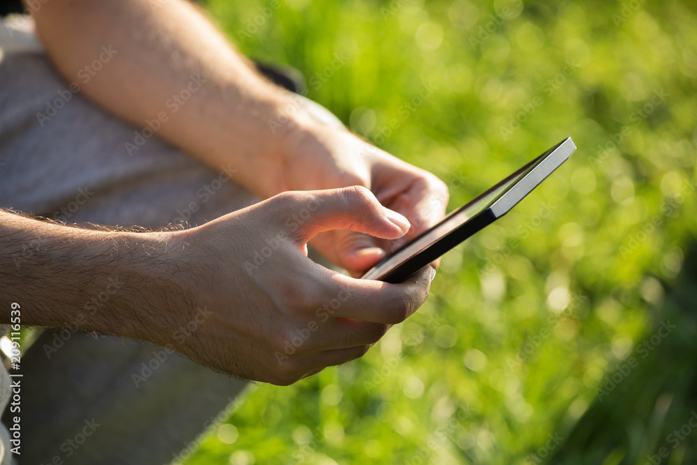 Man holding and using smartphone or tablet; obscured face, close-up