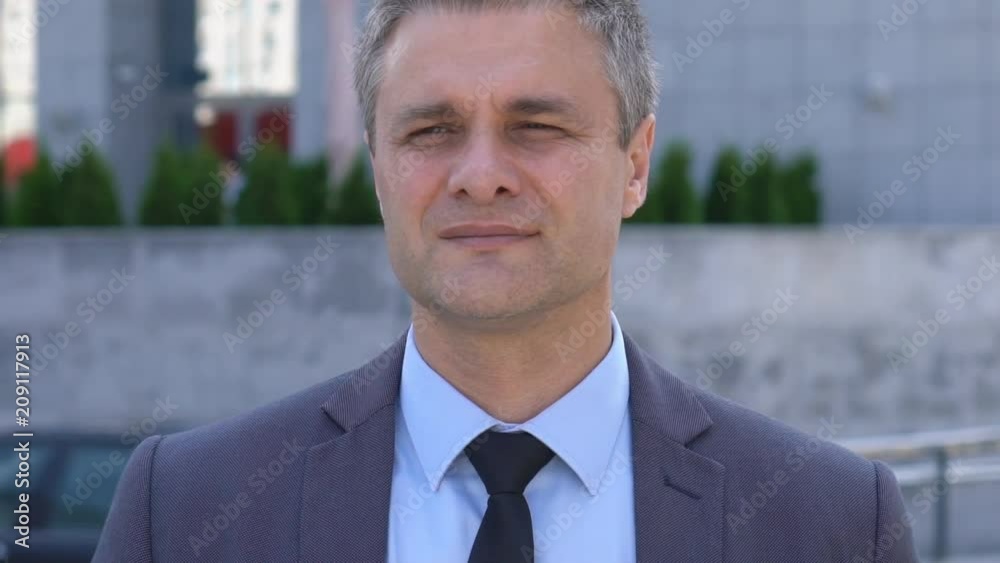 attractive middle-aged man with gray hair. male close-up portrait. serious business man in a jacket on the background of a glass building. Slow motion attractive middle-aged man with gray hair. male close-up portrait. serious business man in a jacket on the background of a glass building. Slow motion