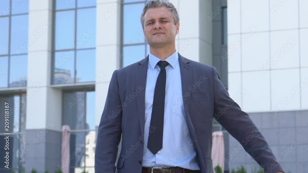 attractive middle-aged man with gray hair. male close-up portrait. serious business man in a jacket on the background of a glass building. Slow motion attractive middle-aged man with gray hair. male close-up portrait. serious business man in a jacket on the background of a glass building. Slow motion