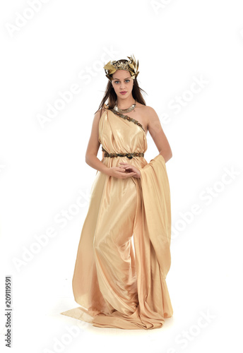full length portrait of brunette woman wearing long golden grecian gown  standing pose. isolated on white studio background.