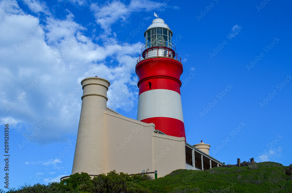 Beautiful lighthouse. Red and white lighthouse, view from bottom, blue sky with clouds on background