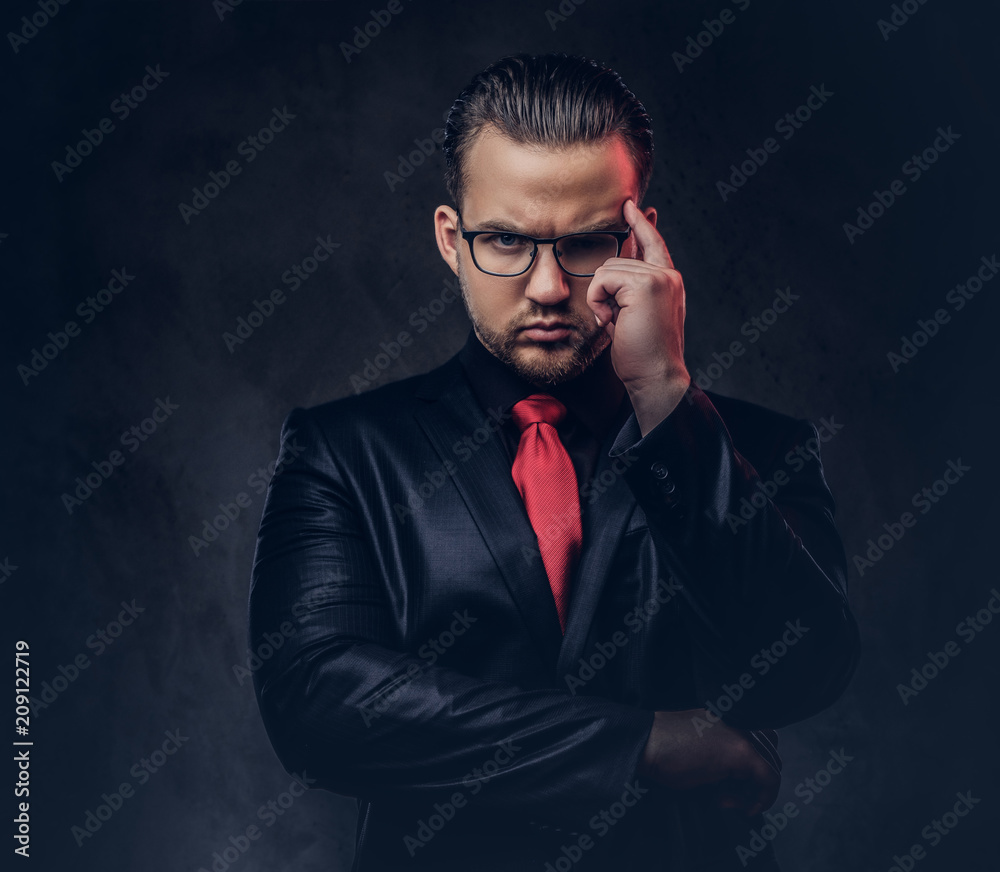 Portrait of a pensive stylish male in a black suit and red tie. Portrait of a pensive stylish male in a black suit and red tie.