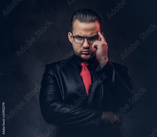 Portrait of a pensive stylish male in a black suit and red tie.