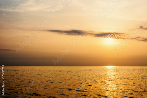 Beautiful nature landscape of colorful sky and warm orange light of the sun at sunset over the sea during summer for background in Thailand