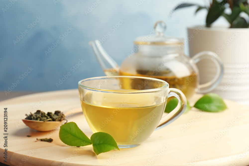 Cup of hot aromatic tea and teapot on table Cup of hot aromatic tea and teapot on table