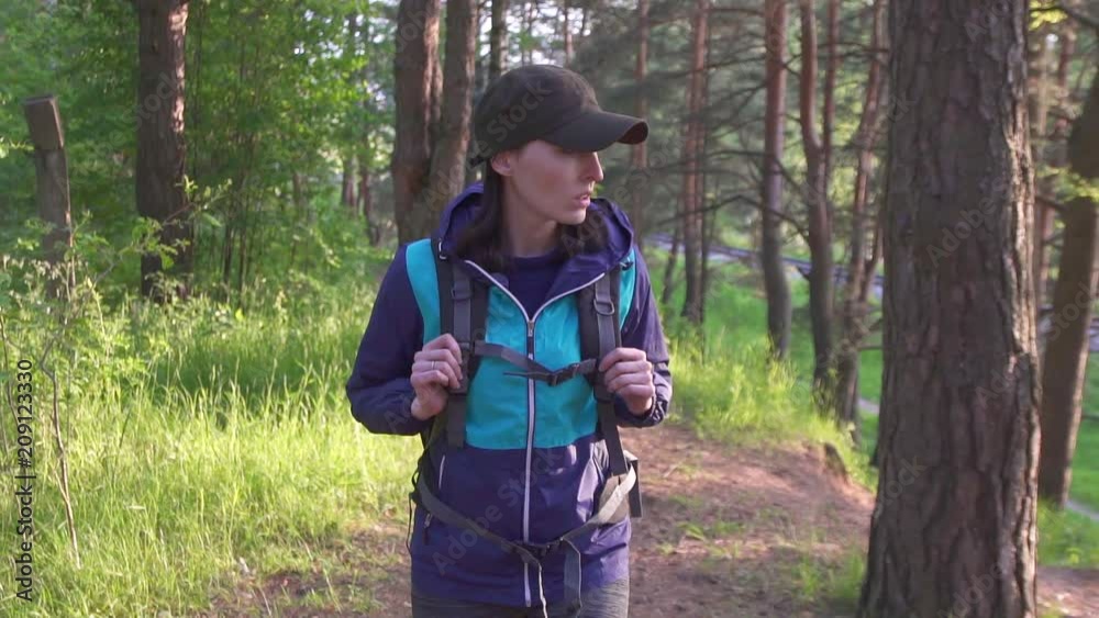 girl tourist with a big backpack goes in the pine forest at sunset girl tourist with a big backpack goes in the pine forest at sunset