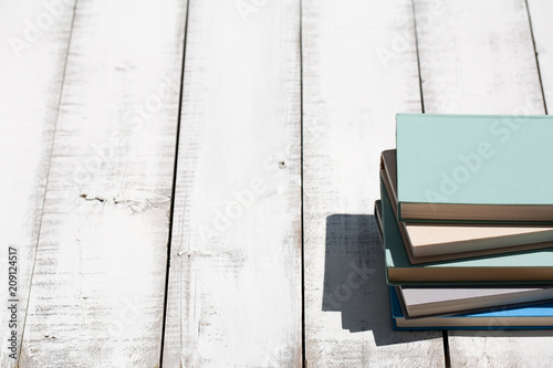 Stack of books on a white beach boardwalk in direct sunlight