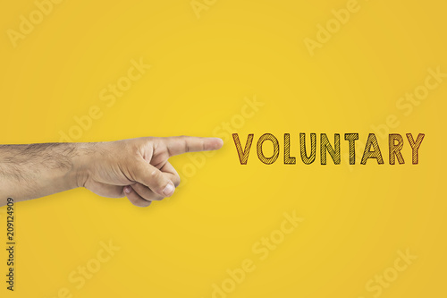 voluntary concept. A man's pointing hand next to the inscription: voluntary on yellow background photo