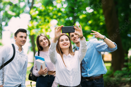 Group of teenager students doing selfie over the university building. Four young happy student making selfie and smiling outdoors.