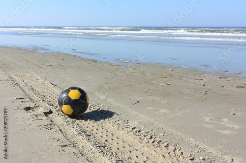Yellow and black soccer ball on the beach