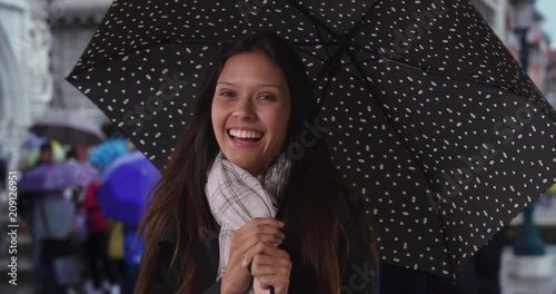 Female tourist smiling in Venice during a rain storm smiling at the camera, Millennial woman in the city by canals with polka dot umbrella, 4k