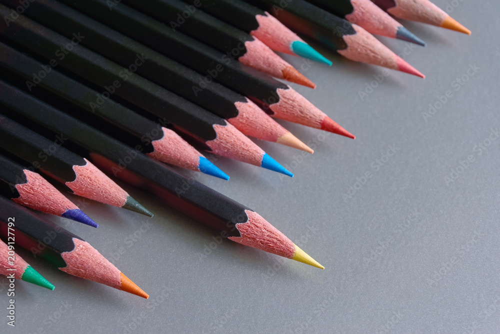 Close-up of an row of black colored pencils against a grey metallic background Close-up of an row of black colored pencils against a grey metallic background