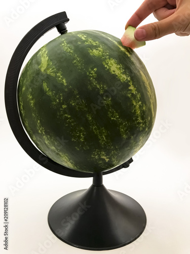 A whole watermelon on a black pedestal and hand on a white background