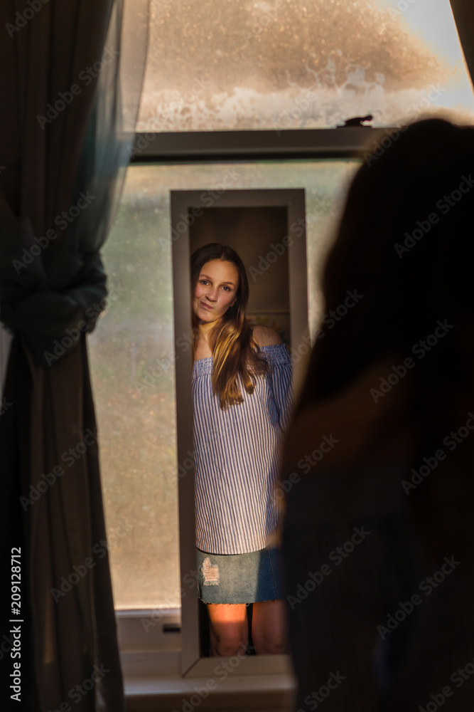 teen girl looking at herself in the mirror at home teen girl looking at herself in the mirror at home