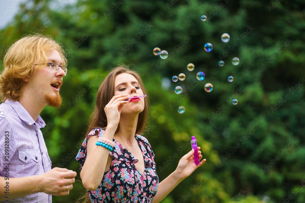Couple blowing soap bubbles, having fun
