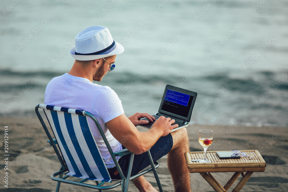 Man working with computer on the beach. Freelancer working