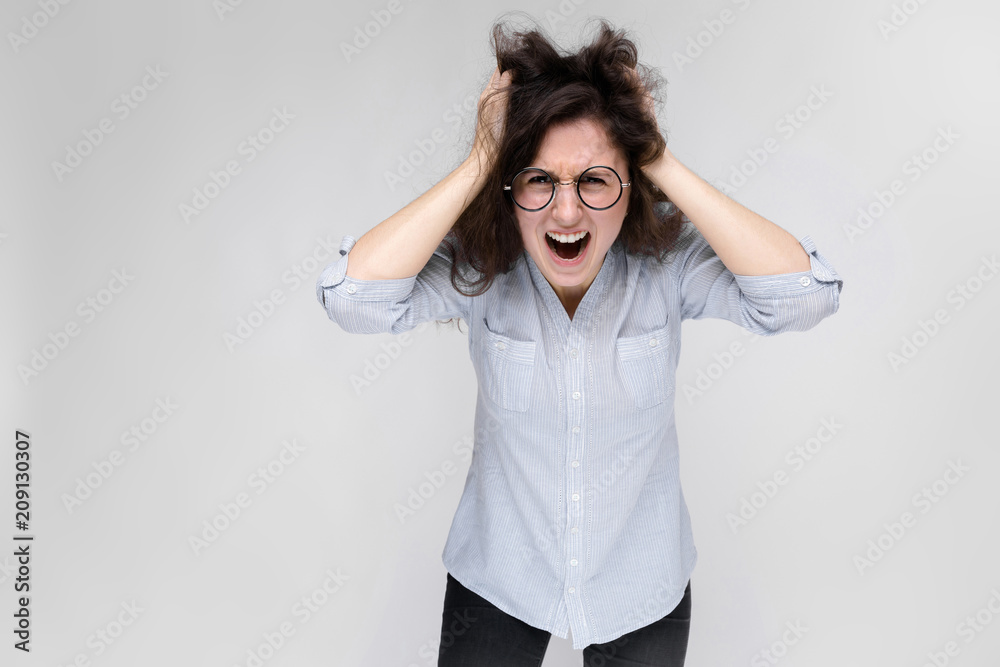 Young brunette girl with glasses. The girl grabbed her head and shouted. Young brunette girl with glasses. The girl grabbed her head and shouted.