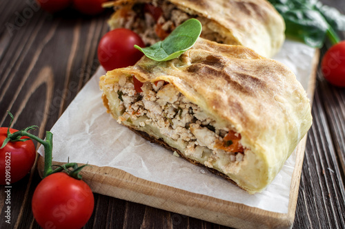 Homemade strudel with meat on a wooden background