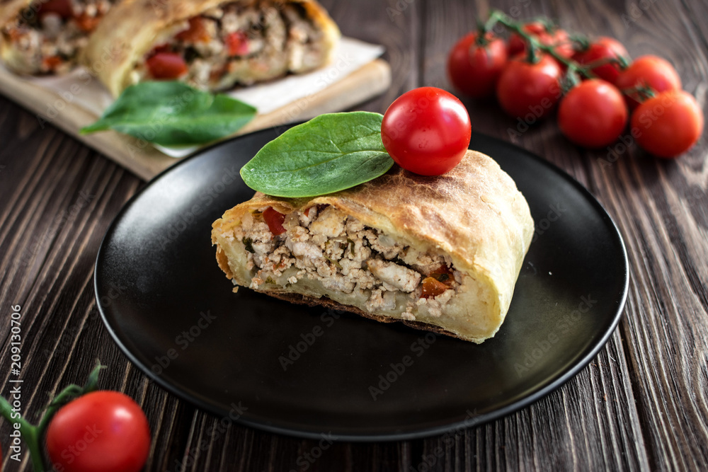 Homemade strudel with meat on a wooden background