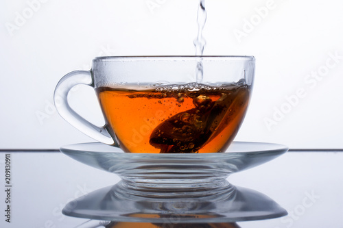 in a transparent cup of tea is poured, black tea is poured