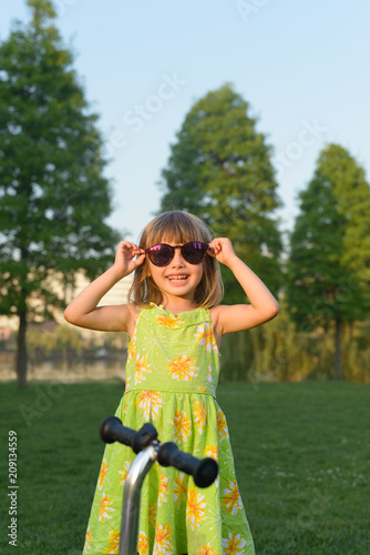 Funny girl posing with larger sunglesses outdoor in the park photo