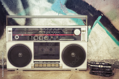 Retro boombox radio with cassettes on a graffiti background / Vintage ghetto blaster with plenty of musical cassettes on grungy background with graffiti. 