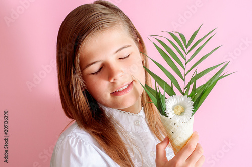 girl holding ice cream cone with yellow flowers and looking at camera on pink photo