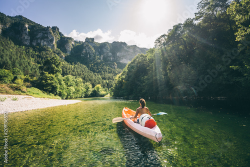 paddler in a canoe on a river in a lush green valley photo