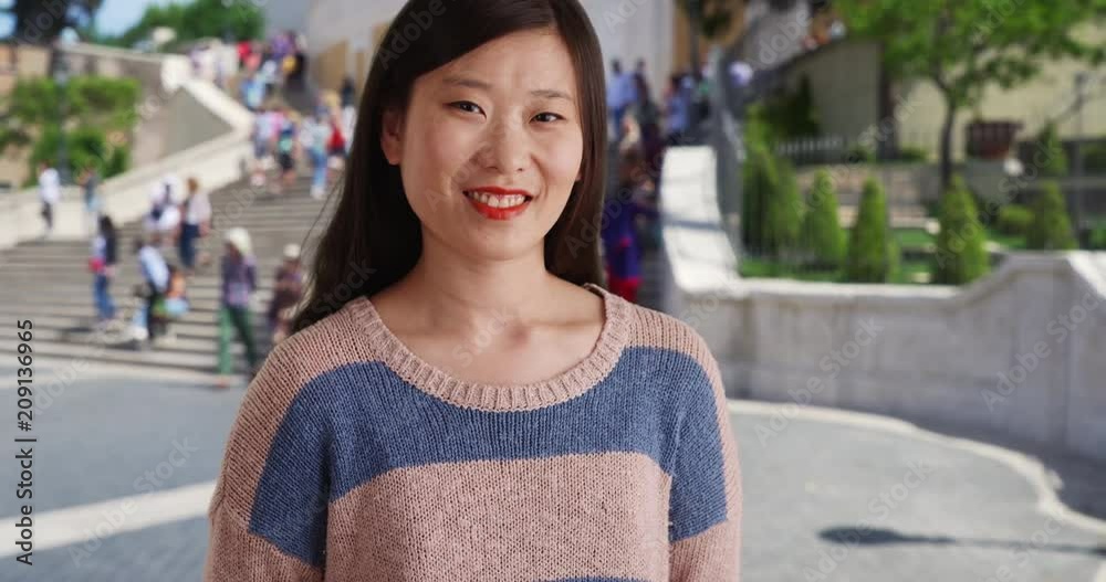 Smiling millennial woman looking joyful and wearing a blue striped sweater in front Spanish Steps, Close up of Asian female with happy expression in Rome, 4k Smiling millennial woman looking joyful and wearing a blue striped sweater in front Spanish Steps, Close up of Asian female with happy expression in Rome, 4k