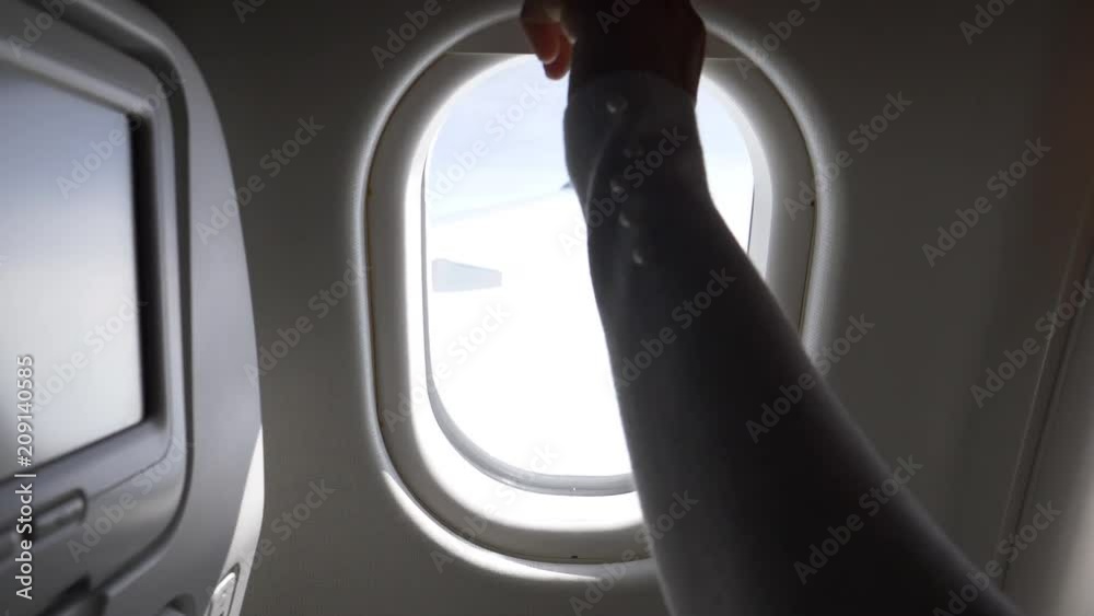 POV, CLOSE UP: Looking through airplane window before female passenger closes the shade. Woman looks through the aeroplane window during a long flight then pulls down the blind to begin the landing.