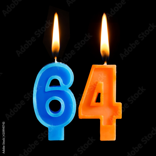 Burning birthday candles in the form of 64 sixty four for cake isolated on black background.