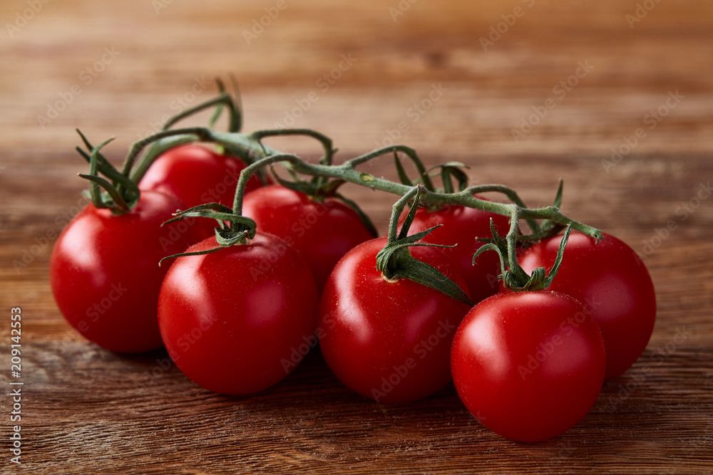 Close-up of a bunch of fresh cherry tomatoes on rustic wooden background, top view, shallow depth of field. Close-up of a bunch of fresh cherry tomatoes on rustic wooden background, top view, shallow depth of field.