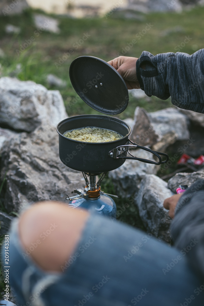noodles cooking on a gas cooker in camping pot foto de Stock Adobe Stock
