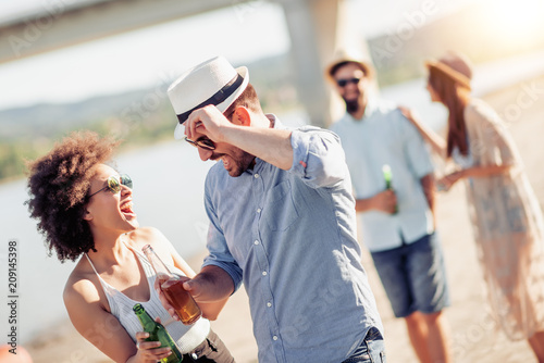 Happy friends drinking together on the beach