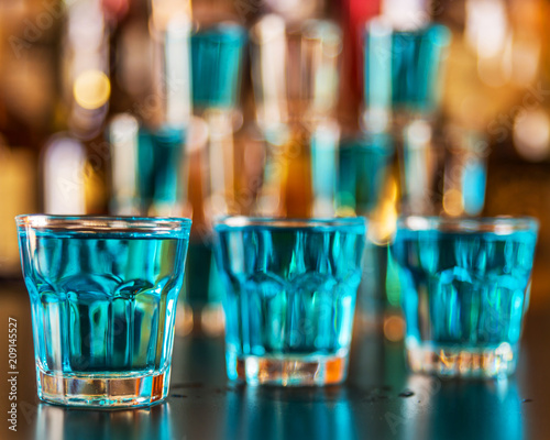 Popular blue drink shot kamikaze on the background of the bar with bottles, a refreshing drink © Q77photo