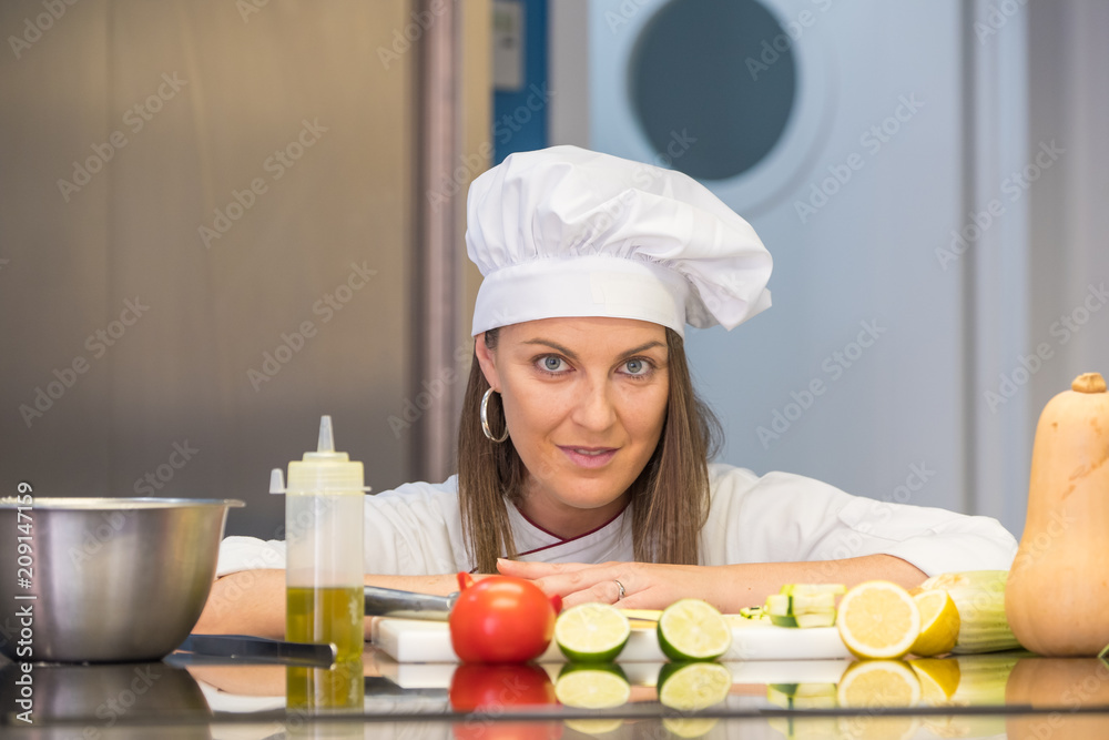 beautiful young cook girl posing on the kitchen counter with their utensils, fruits and vegetables beautiful young cook girl posing on the kitchen counter with their utensils, fruits and vegetables