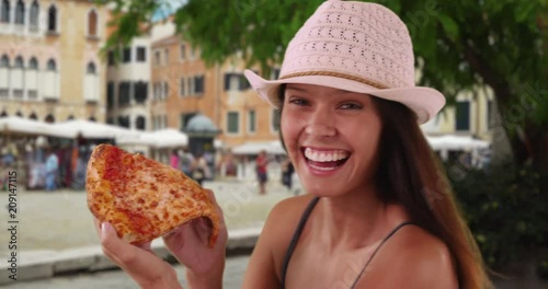 Young tourist woman in trendy fedora enjoying vacation in Italy eating pizza, Close up of cheerful female on Venice street exploring Italian cuisine, 4k