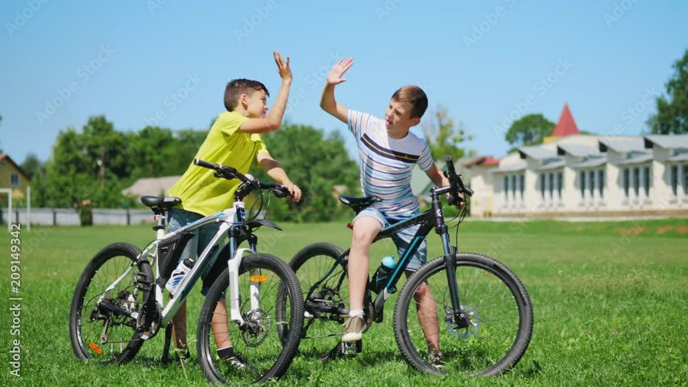 Two little boys with bicycles on the nature communicate with each other, smile. Slow motion Two little boys with bicycles on the nature communicate with each other, smile. Slow motion