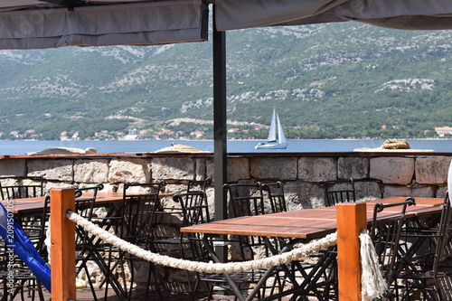 Sea viewing restaurant on the Korcula town promenade and a catamaran background, Korcula island, Croatia