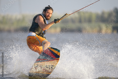 Full-length portrait of caucasain man wakeboarding on the lake photo