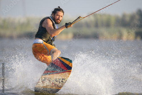 Full-length portrait of caucasain man wakeboarding on the lake